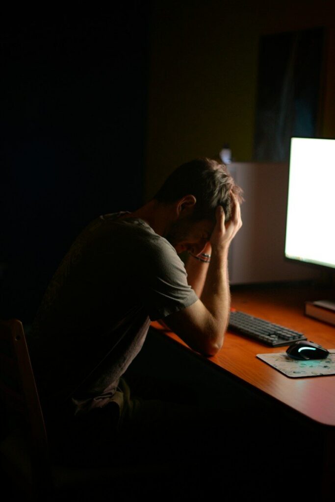 Exhausted man with his head in his hands at a desk late at night