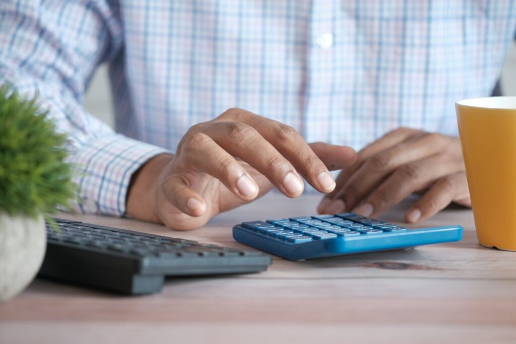Man using a calculator to work out the real hourly wage of a part-time job